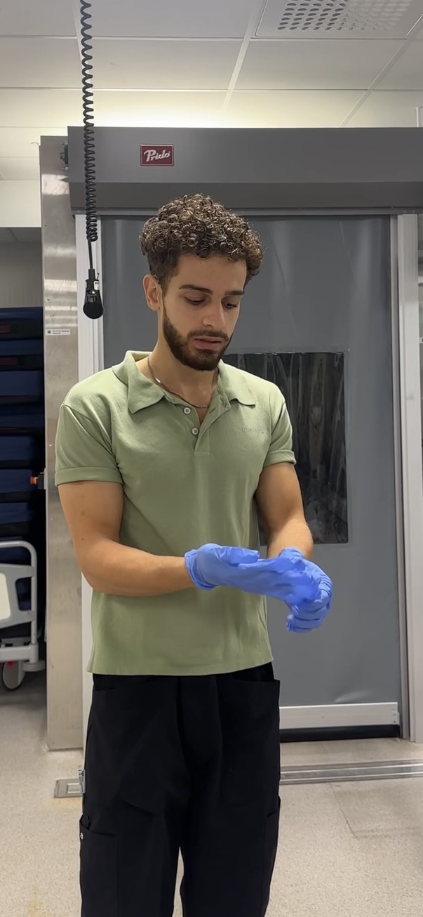 Nezar Naser tar på sig handskar under ett skift som patienttransportör på Kungälvs sjukhus